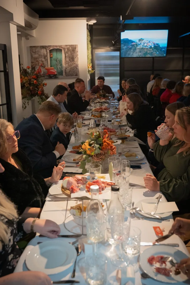 A long banquet table of guests dining and toasting together at La Botte D'Oro, Leichhardt
